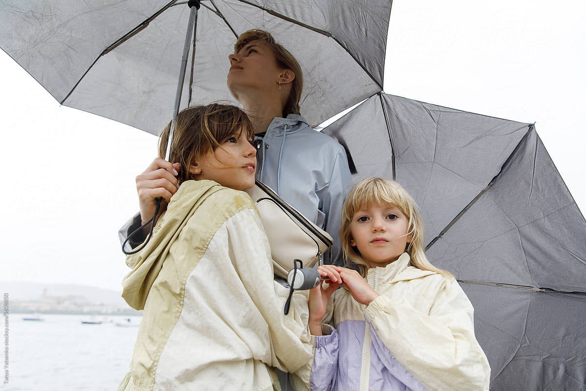 Two girlsl with mother in the rain