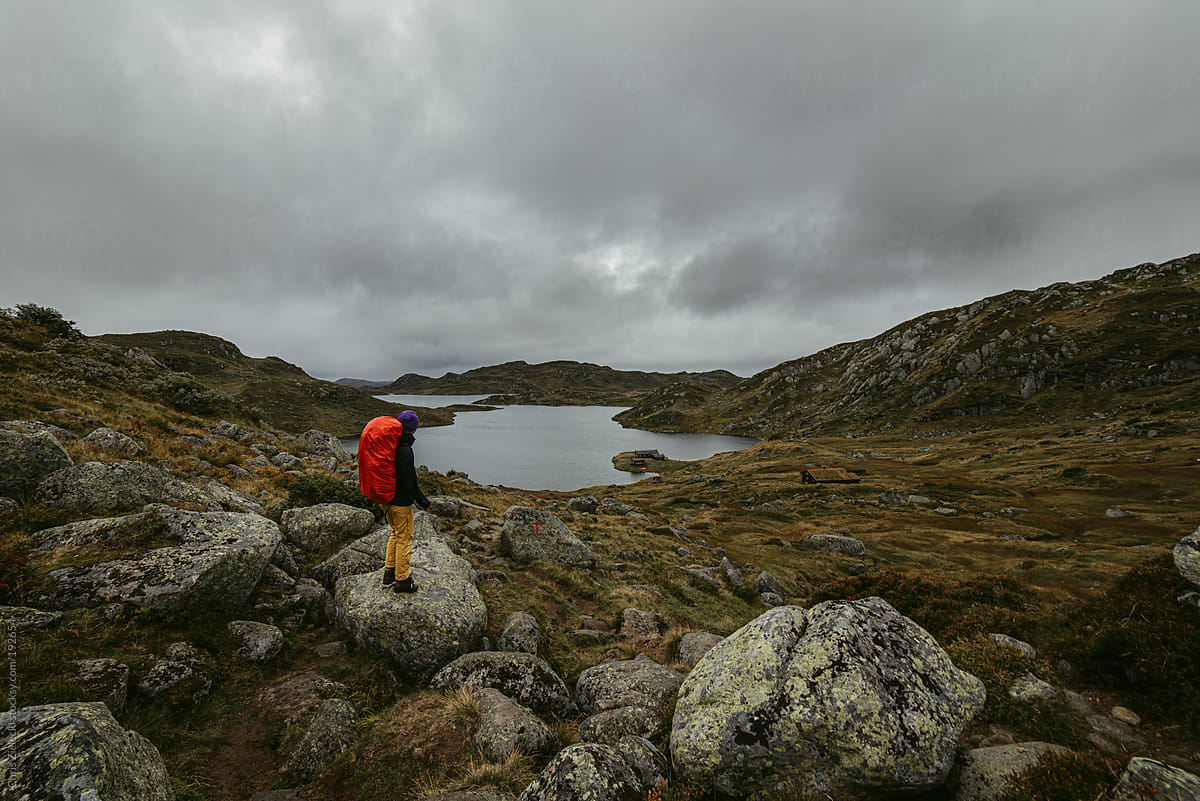 Anonymous tourist admiring lake and rocky terrain