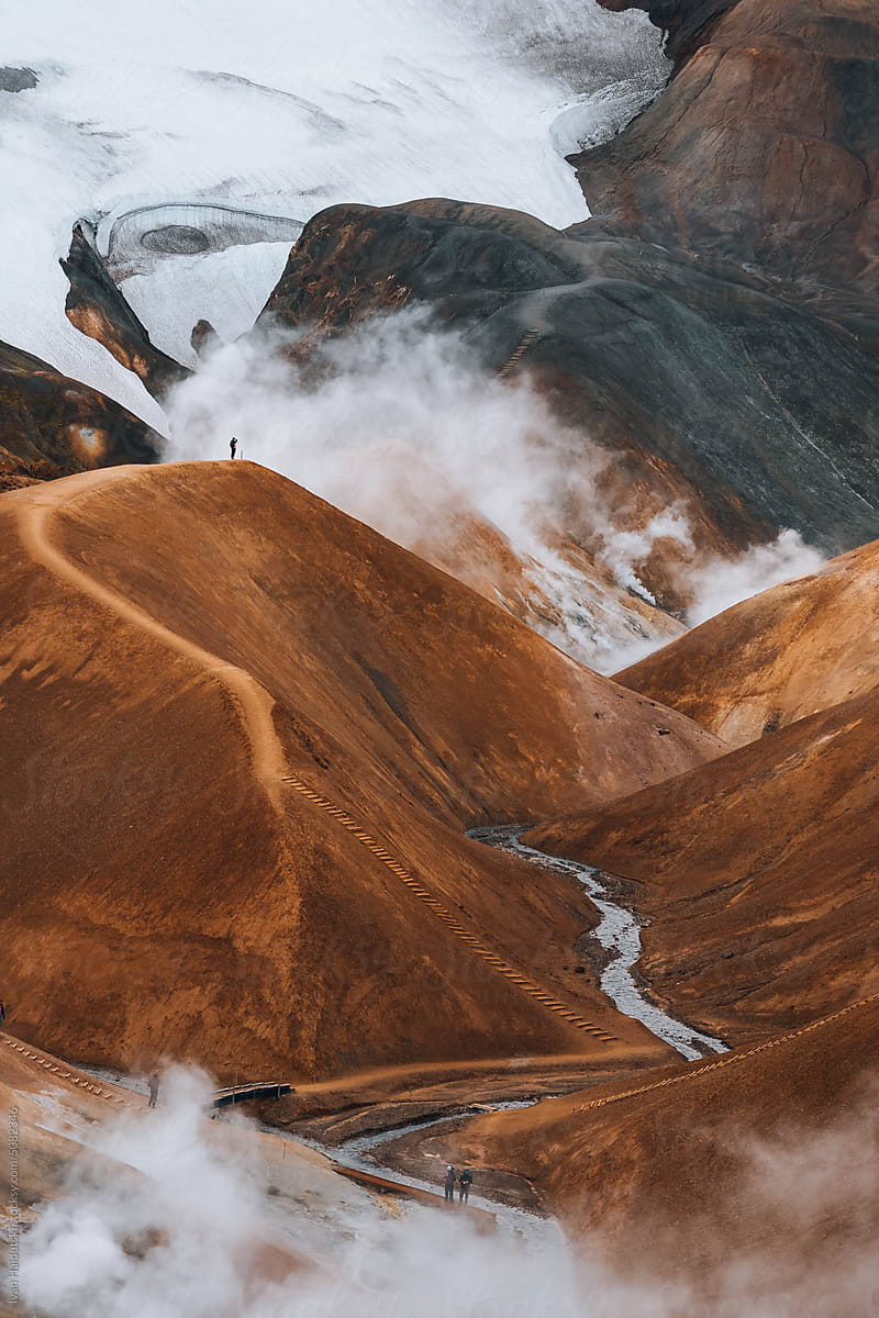 Hiker exploring golden brown landscape of Iceland\'s geothermal area.