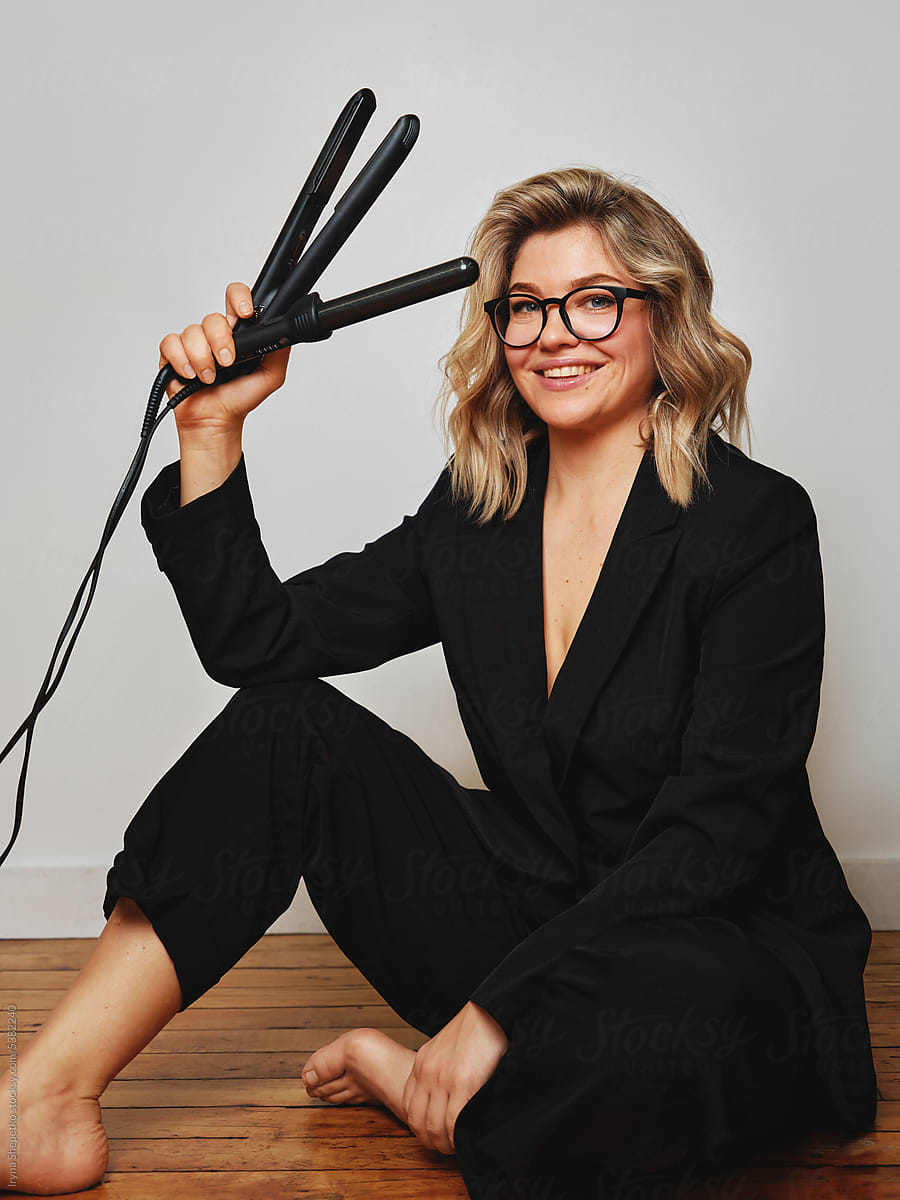 Hairdresser with curling irons sitting on floor in studio