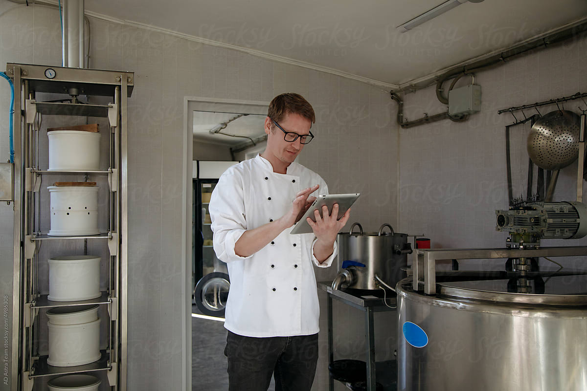 A worker stands at the cheese factory with a tablet in his hands