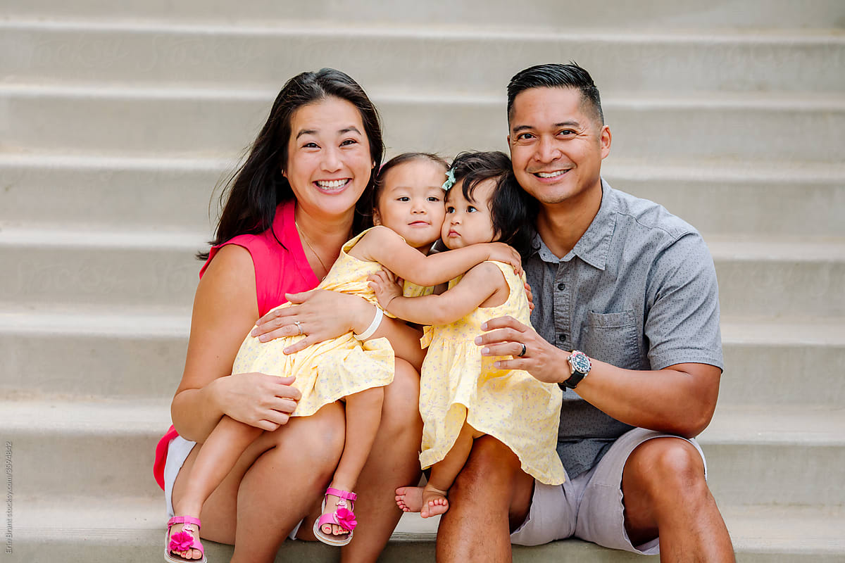 Beautiful asian family on steps with young hugging daughters