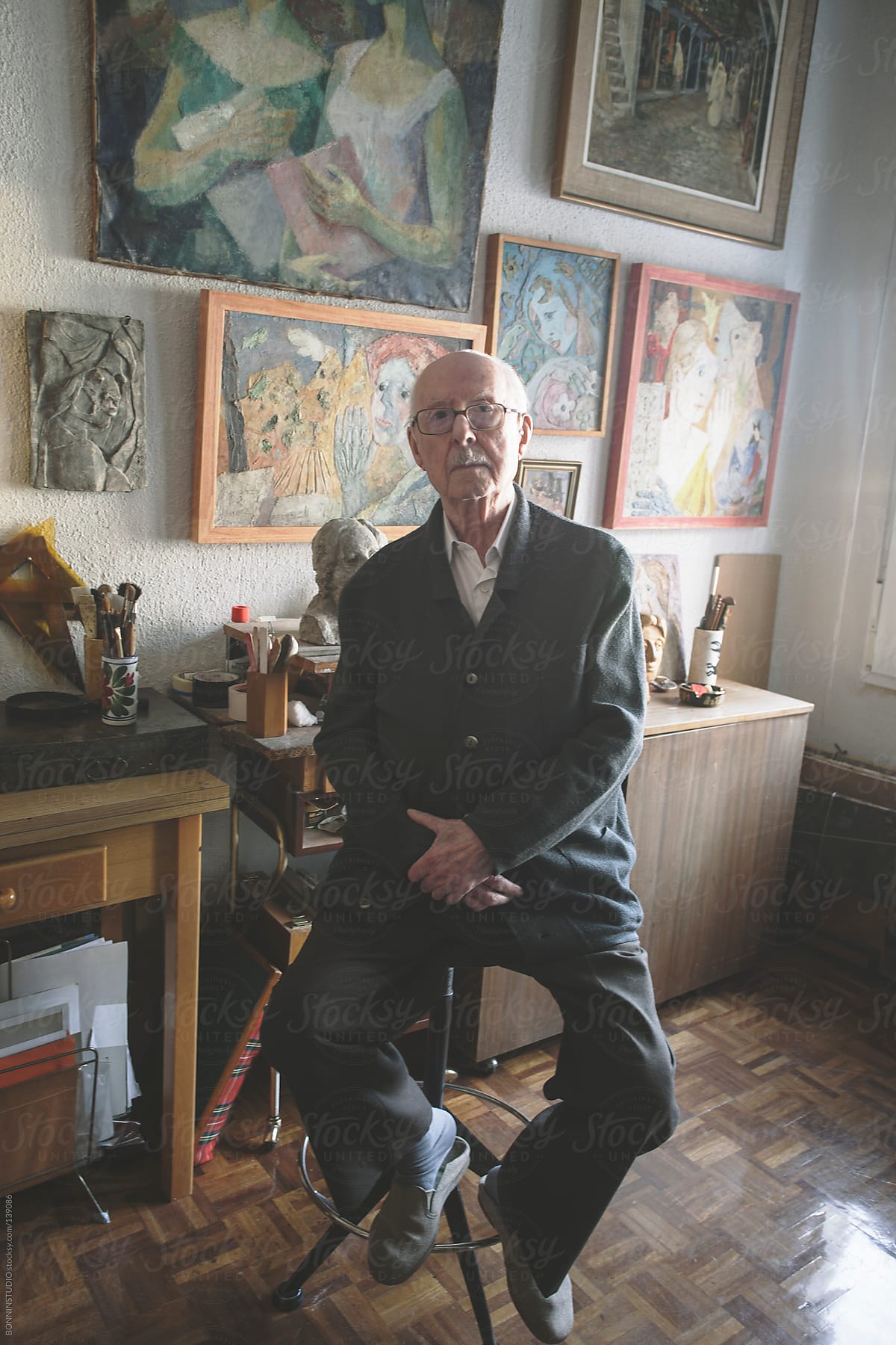 Old man sitting on his studio of painting and sculpture.