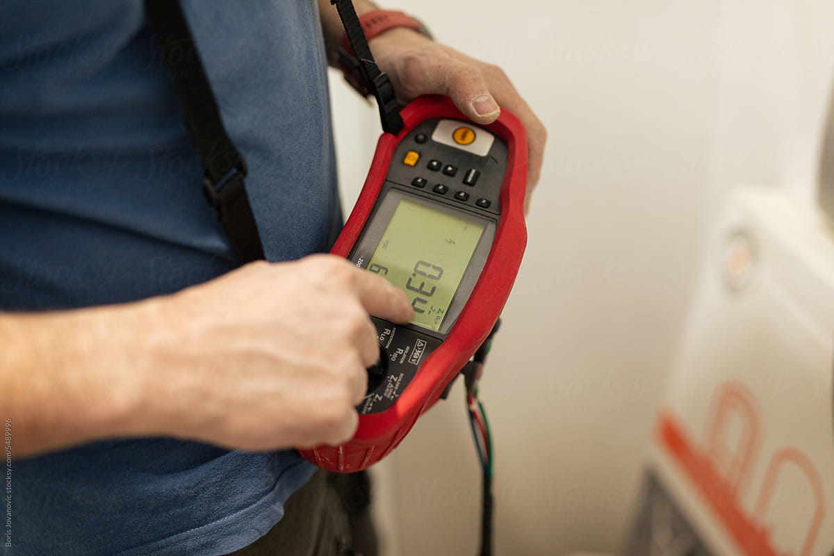 Electrician measures the voltage with a digital instrument