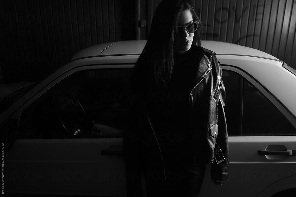 Mysterious Woman Wearing Black Standing Next To The Car In Garage Del Colaborador De Stocksy 