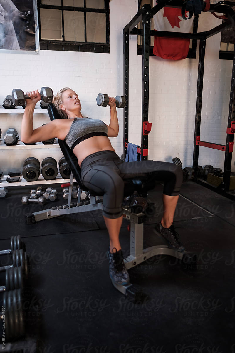 A Woman Performs A Dumbbell Chest Press Exercise. by Stocksy Contributor  Riley JB - Stocksy
