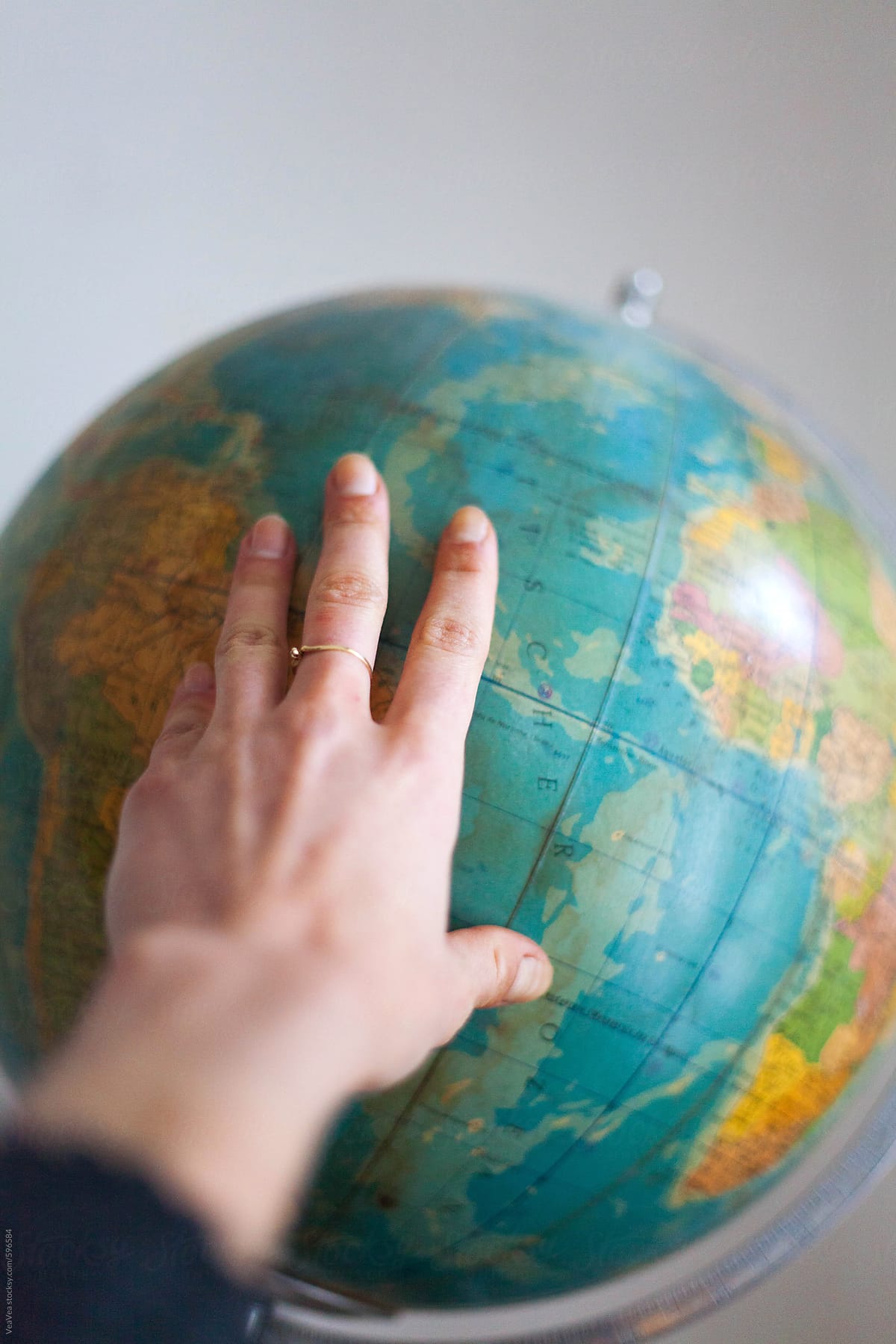 Female hand on a globe indoors