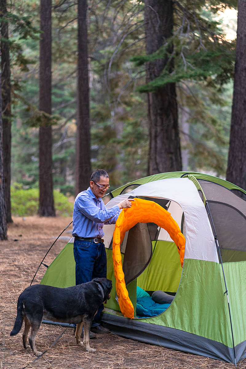 Man and dog setting up camping tent and sleeping pad