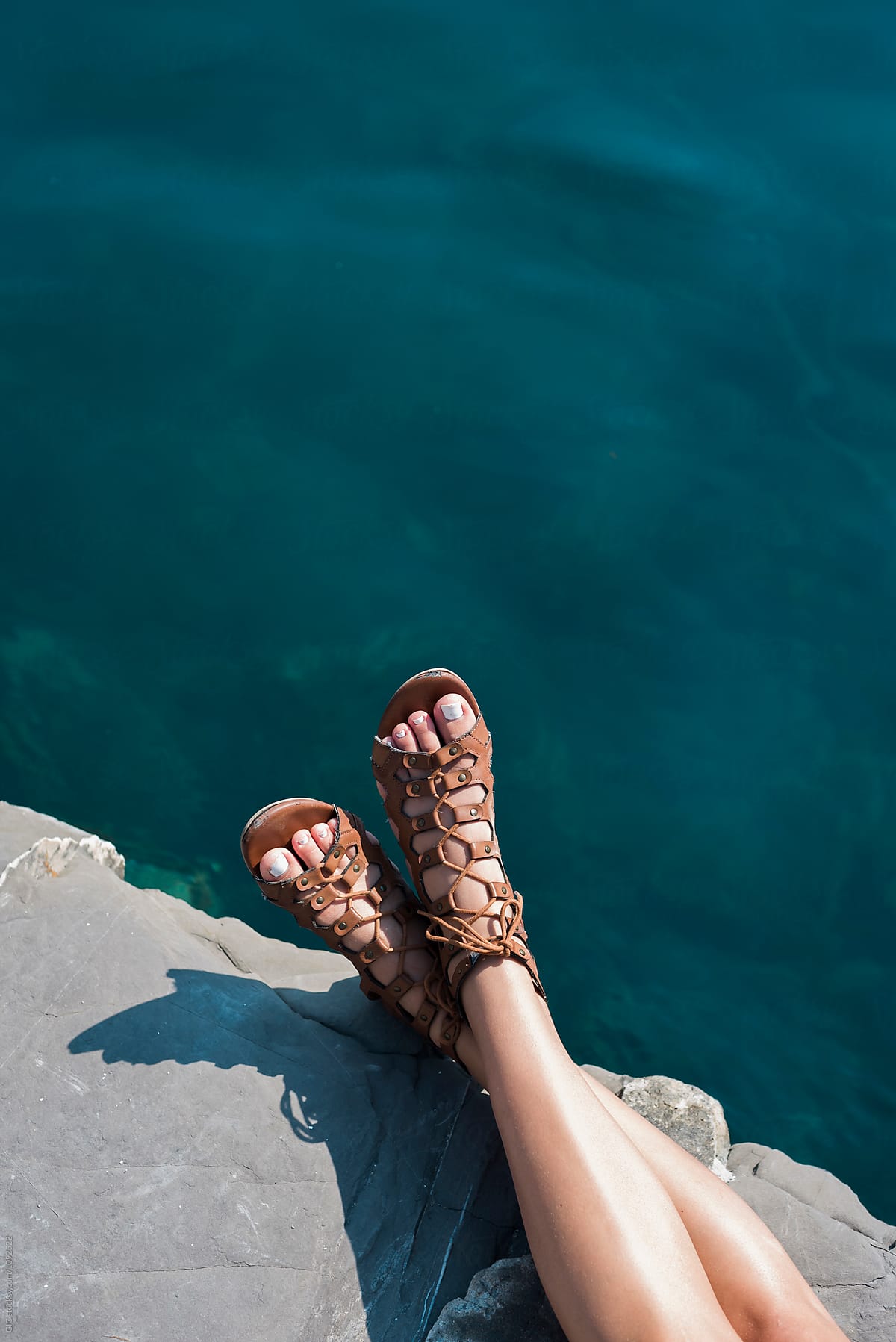 Foot wearing sandals against water