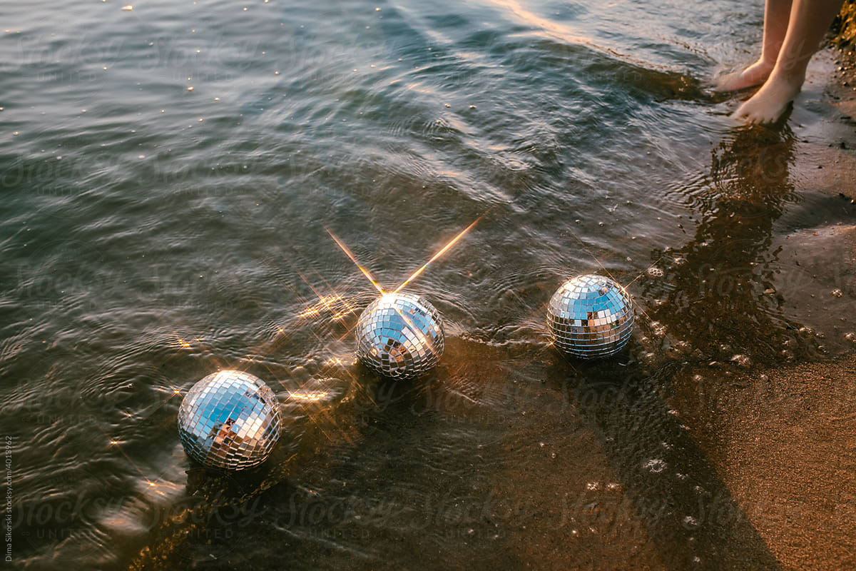 conceptual image from feet in the sea with mirror balls