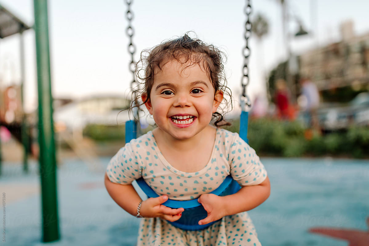 Happy young girl playing on swing