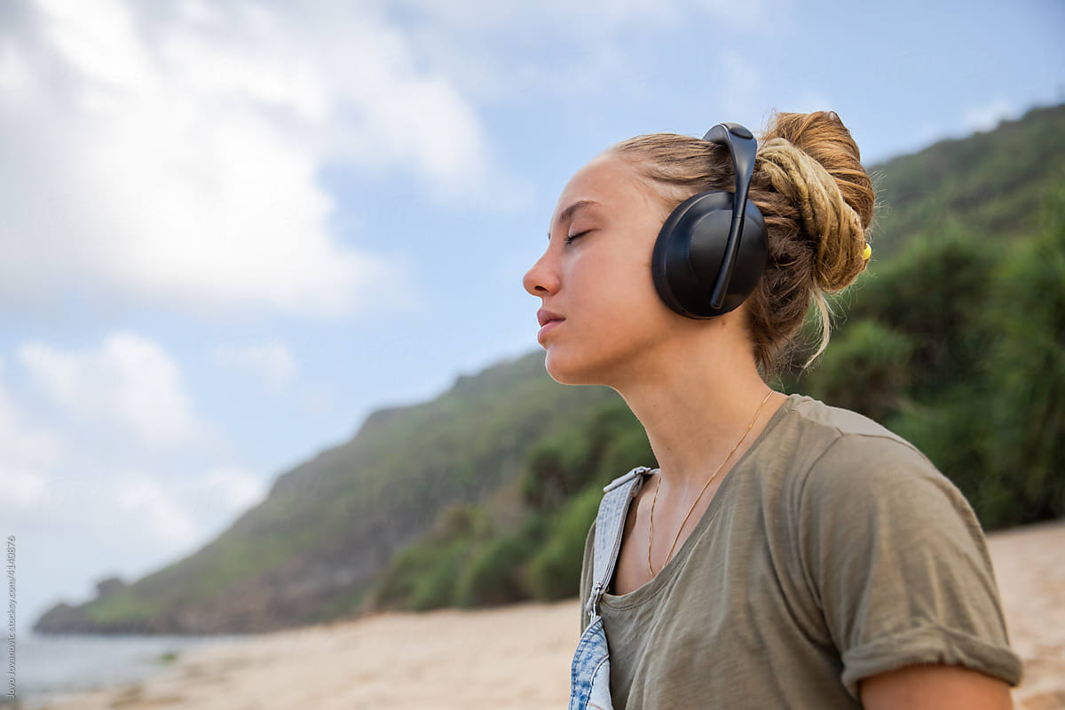 Woman sitting at the beach with headphones