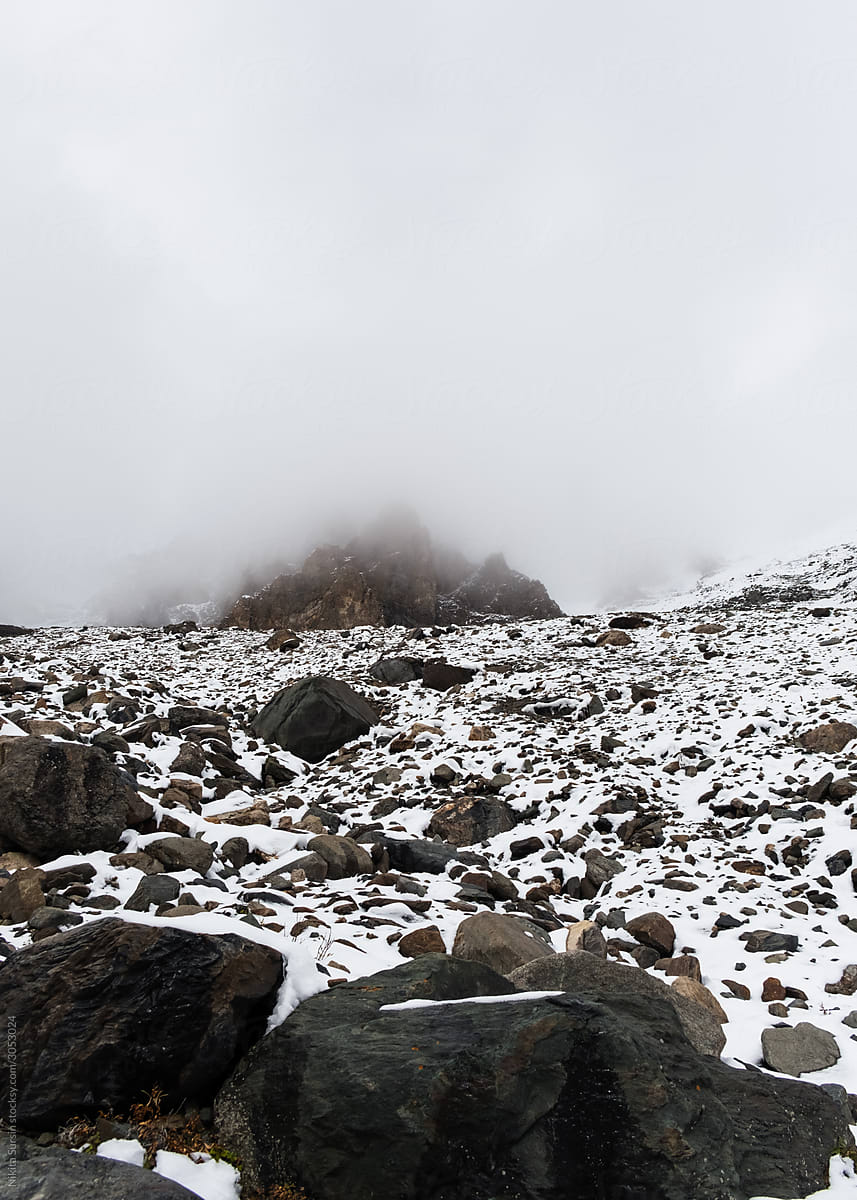 foggy mountains landscape, snowy mountains with huge stones