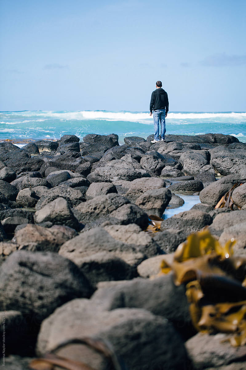 Man Standing On Rocky Beach Looking Out To Beautiful Ocean | Stocksy United
