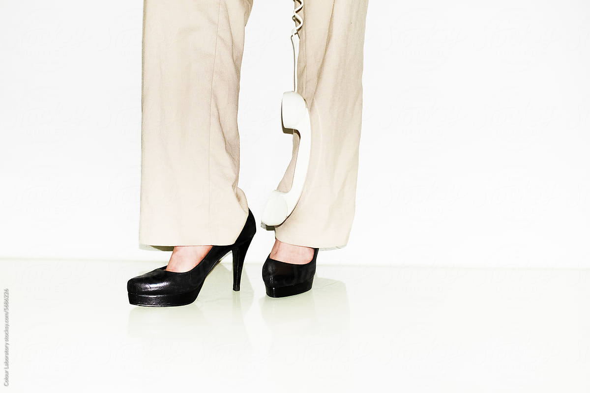 Bosslady with formal trousers and heels holding a landline with flash