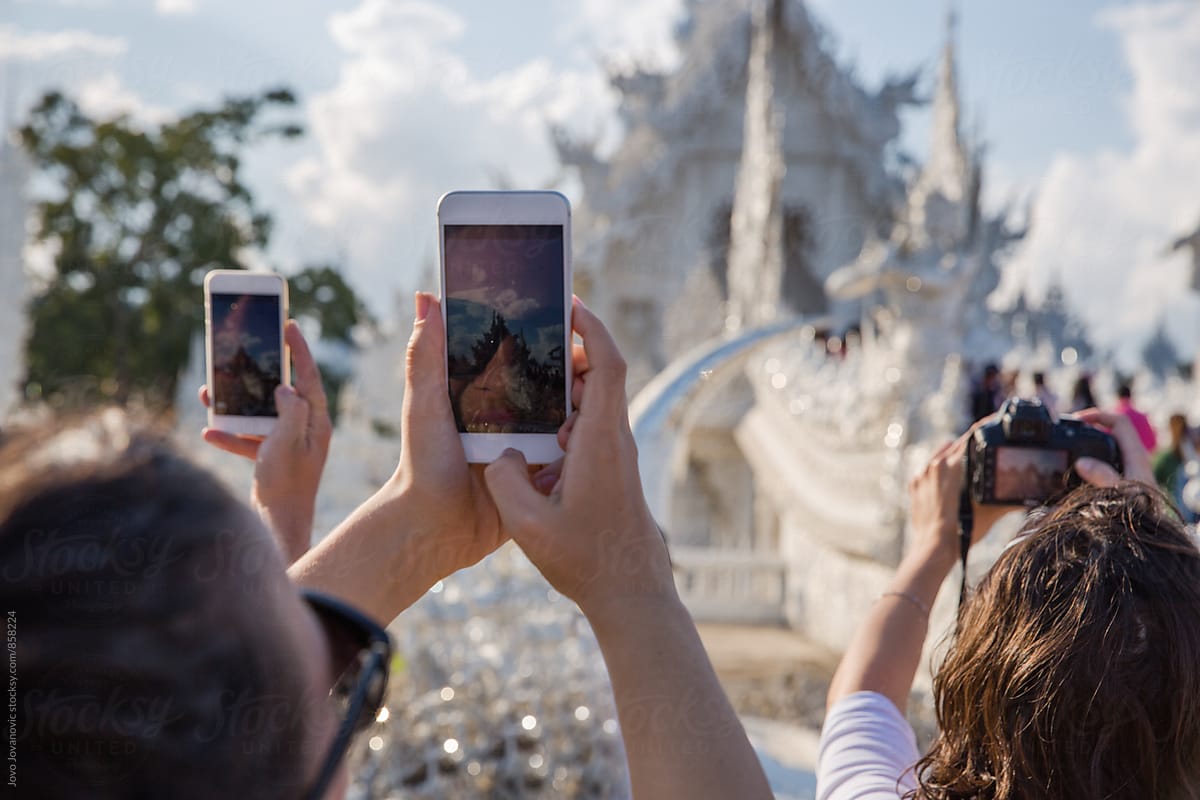 Tourist taking a photo of Wat Rong Khun - the white temple in Thailand