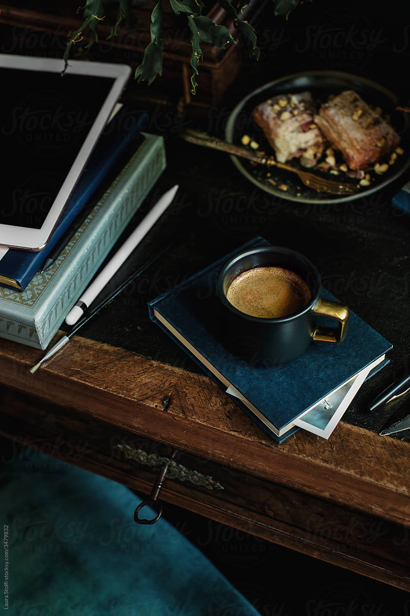 Coffee, strudel cake, tablet and books on vintage wooden desk