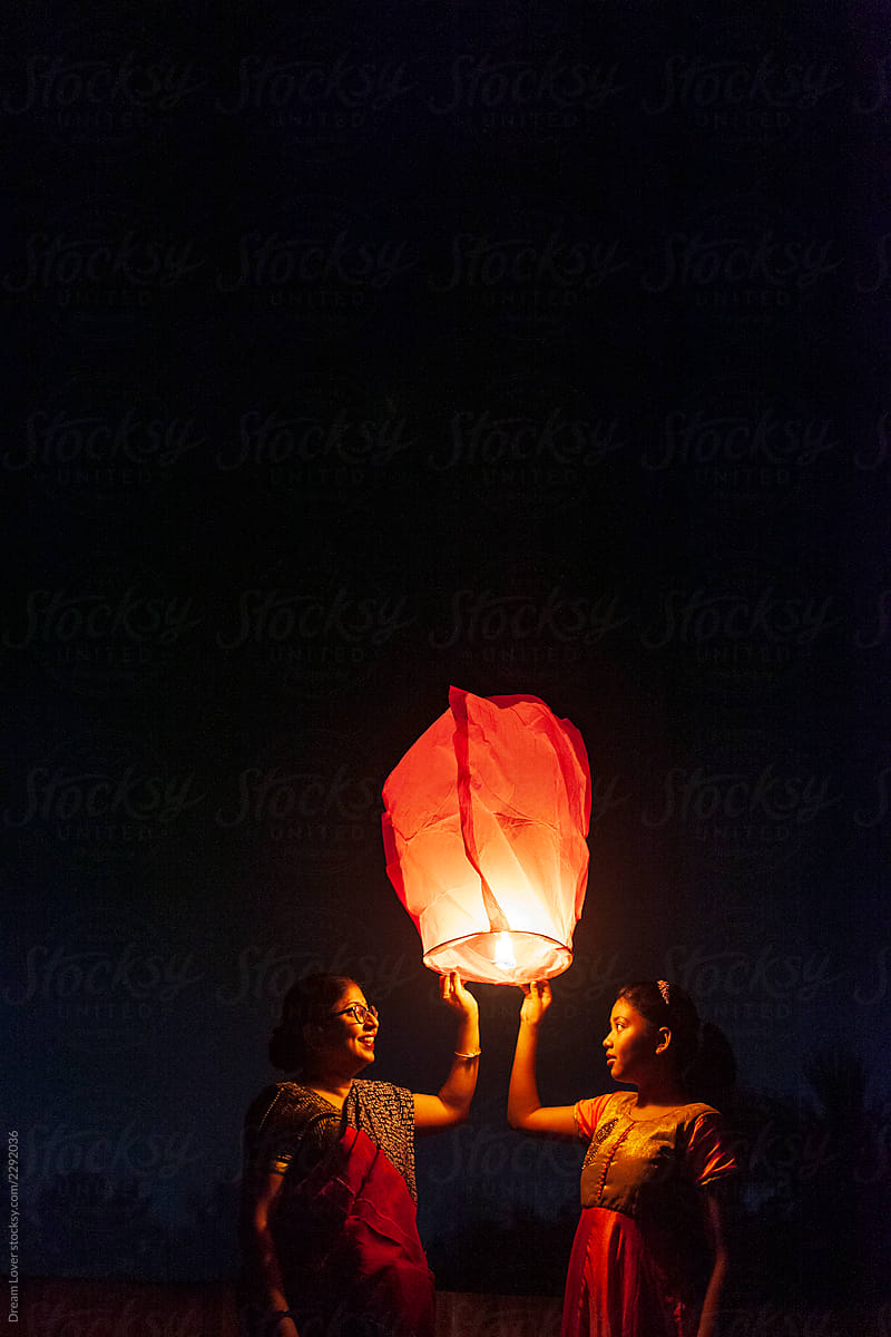 Little Girl And Her Mother Releasing Sky Lantern To The Sky At Twilight