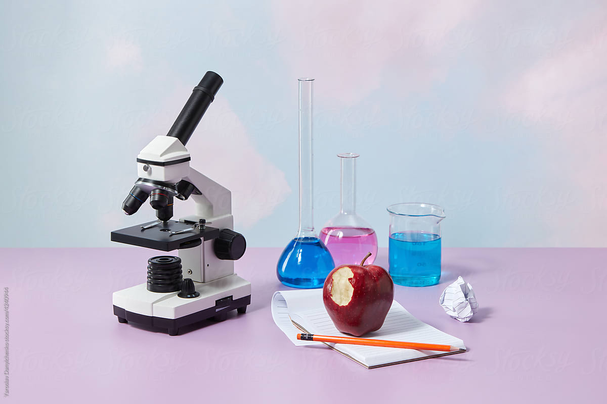 Microscope, red apple and notebook
