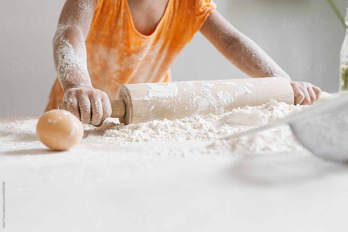 Rolls out dough with a rolling pin while making cakes.
