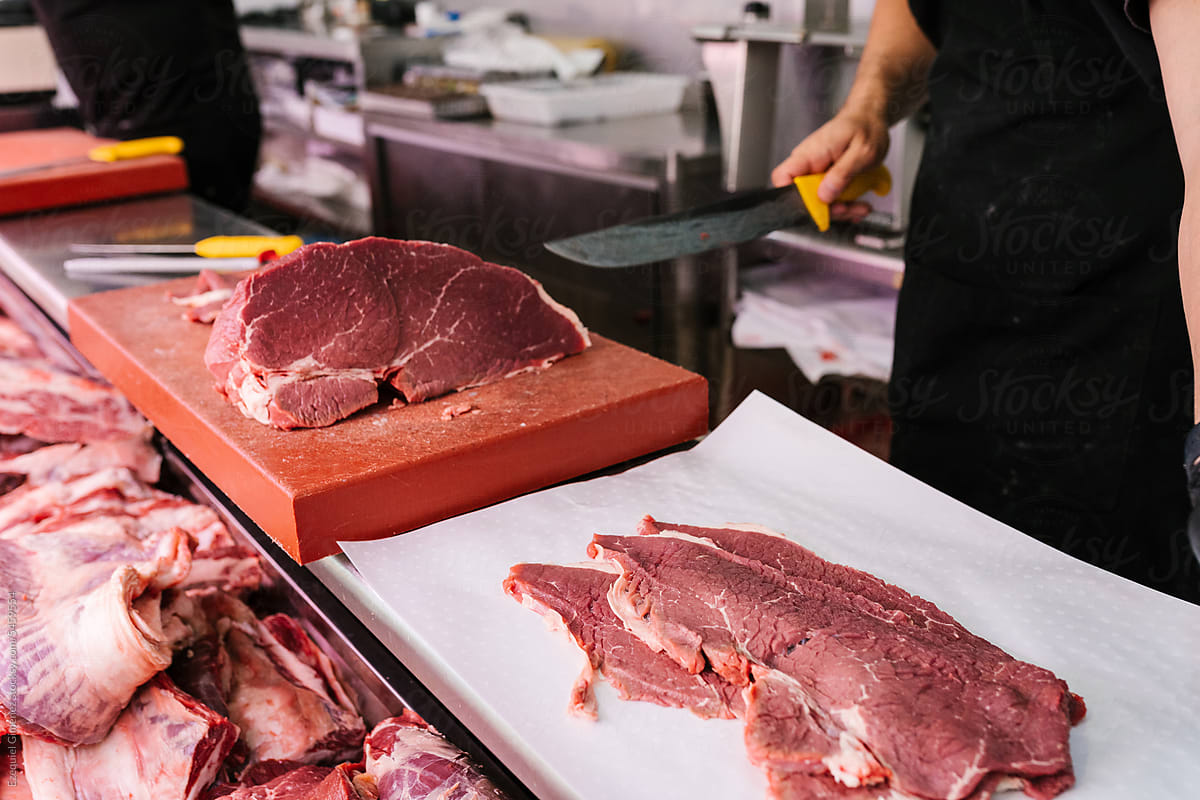 Crop worker cutting raw meat in industrial kitchen