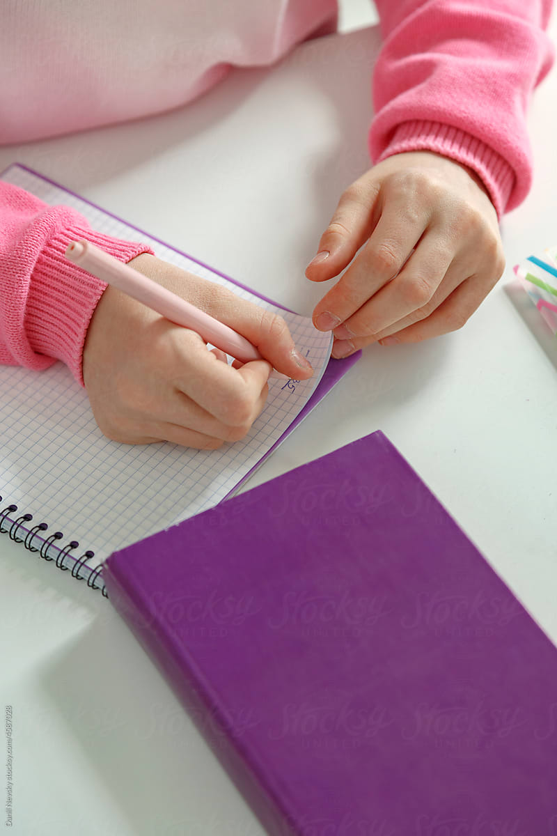 Crop schoolchild writing in notebook