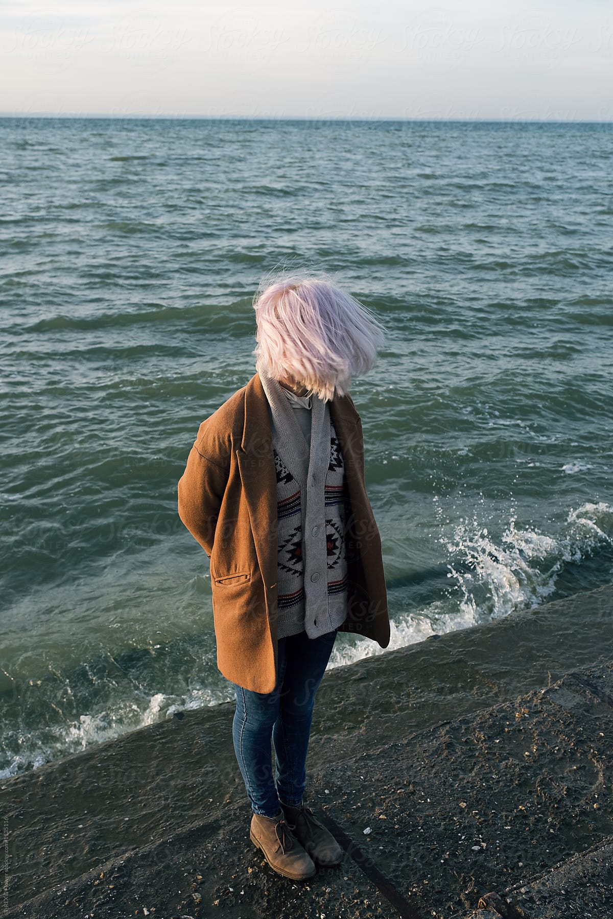 Unrecognizable woman with windy hair on stone pier