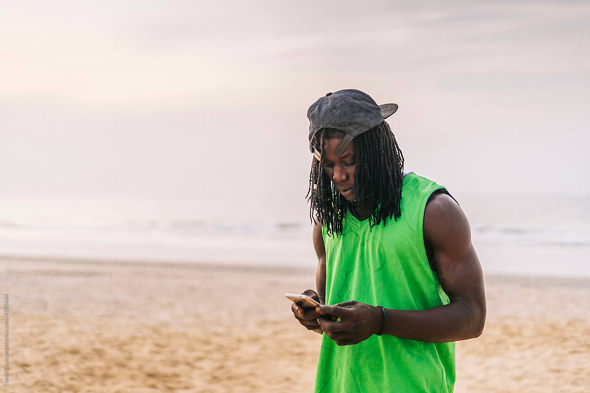 African guy with cellphone on seashore