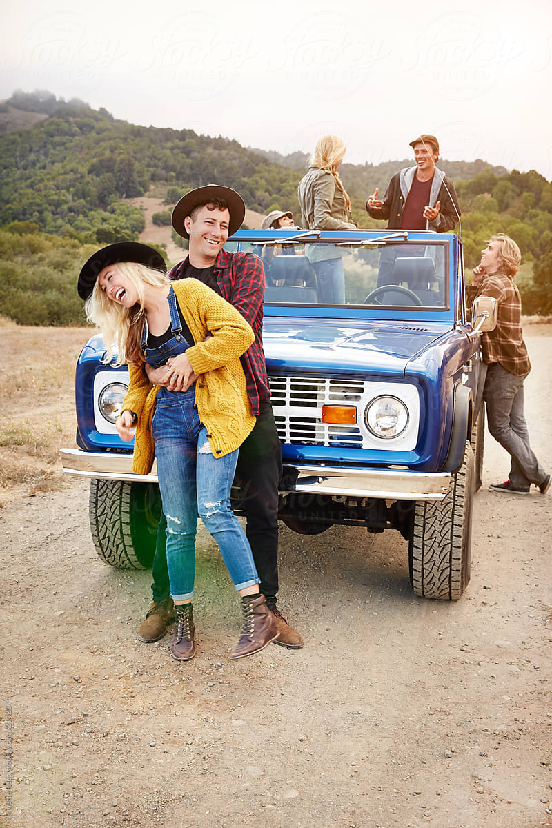 Portrait of couple with group of friends in nature while on road trip laughing