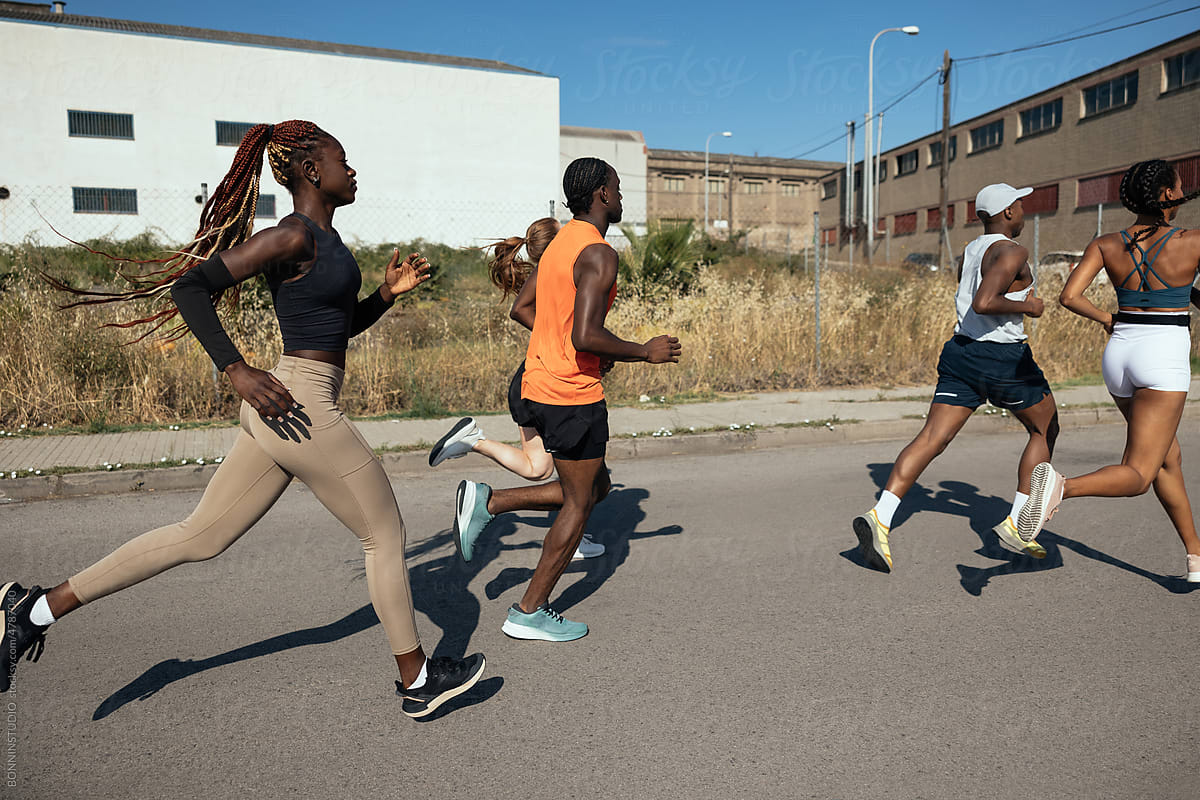 Sportspeople running on road near industrial buildings