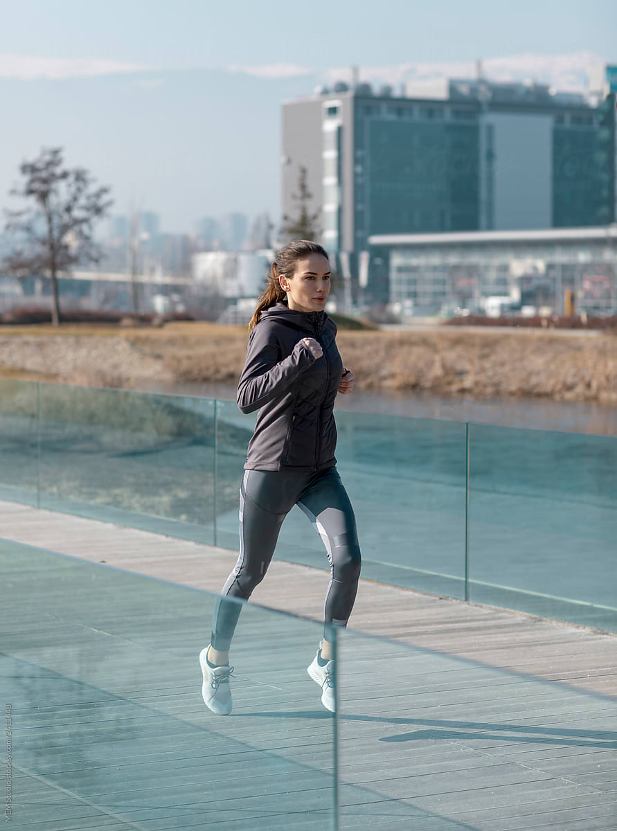 Woman Jogging In A Park Near The City by Stocksy Contributor MEM Studio  - Stocksy