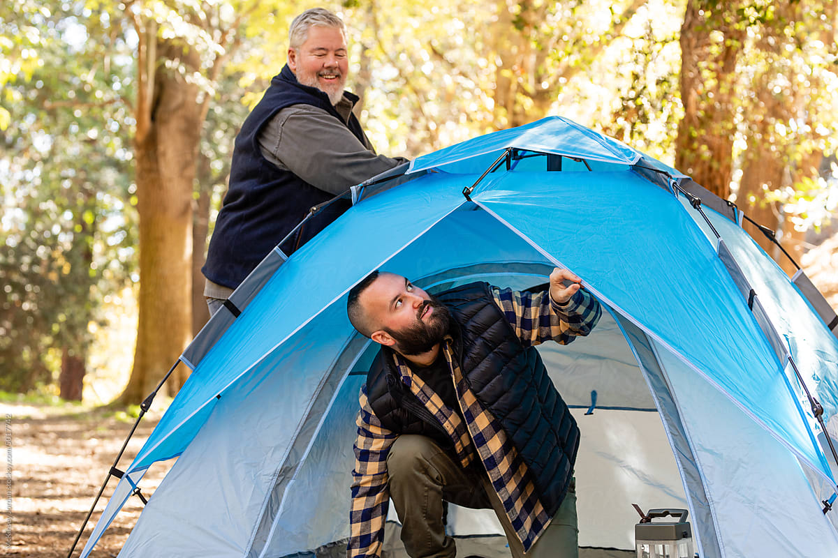 Two Men Happily Set Up Their Campsite In The Woods