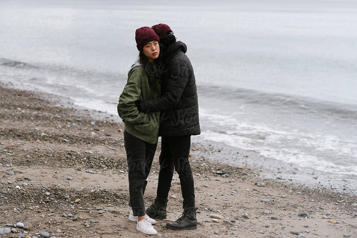 Thoughtful Young Couple Hugging on the Beach
