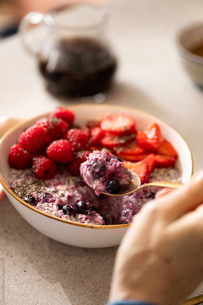 Woman eating healthy overnight oatmeal breakfast with fruit topping
