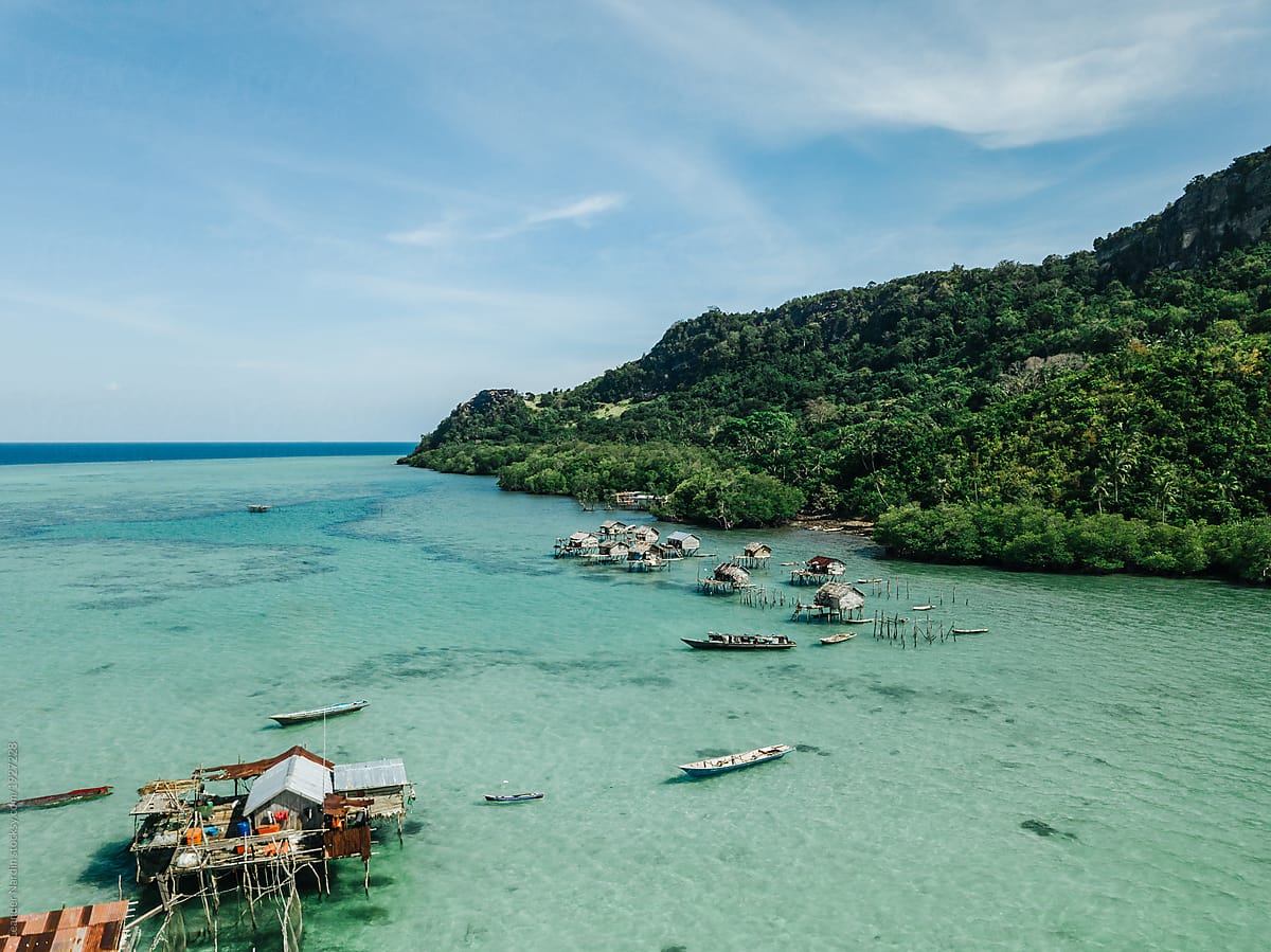 stilt houses from a sea nomads tribe on an emerald reef in front of an island, borneo