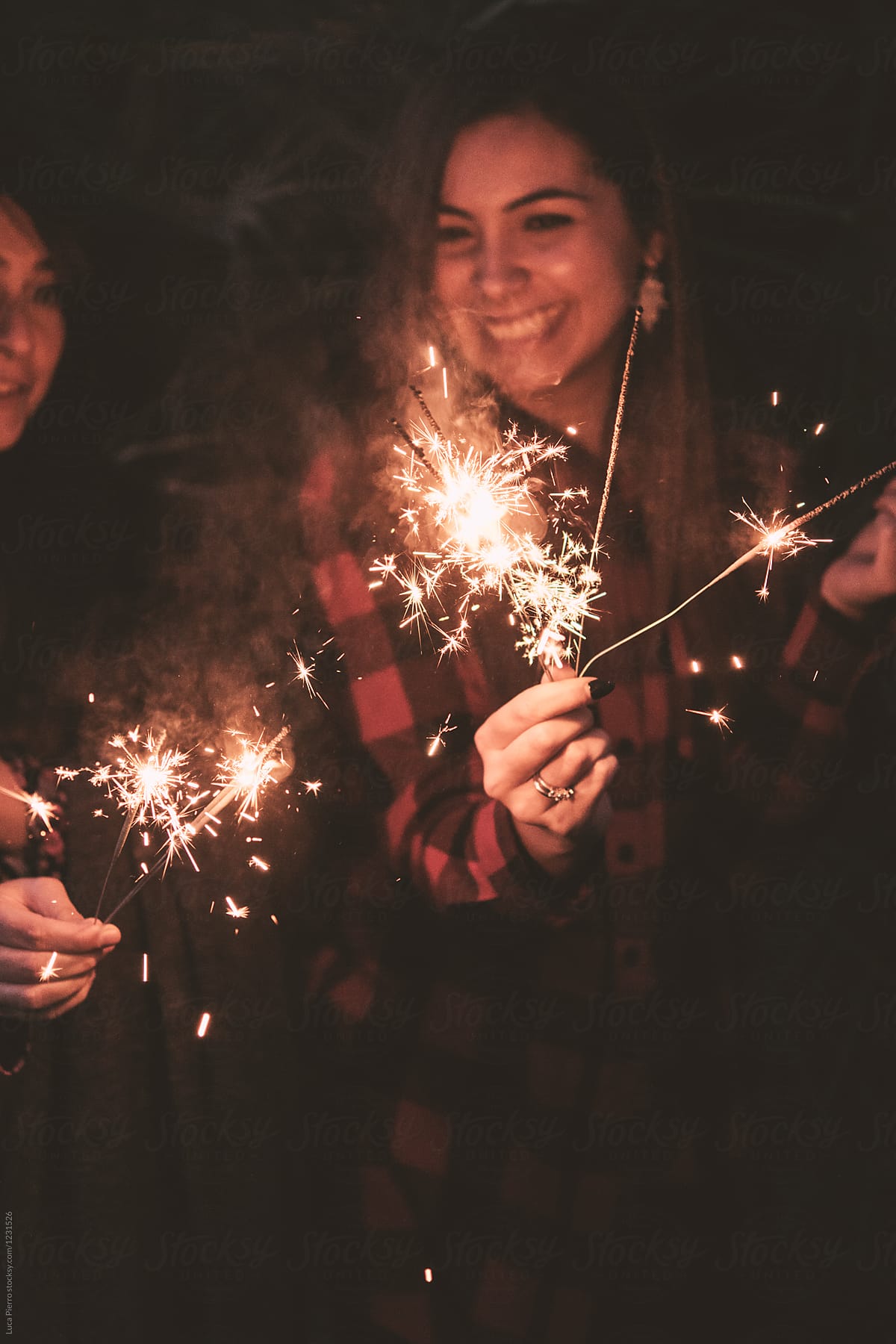 Two woman having fun with sparklers at a party