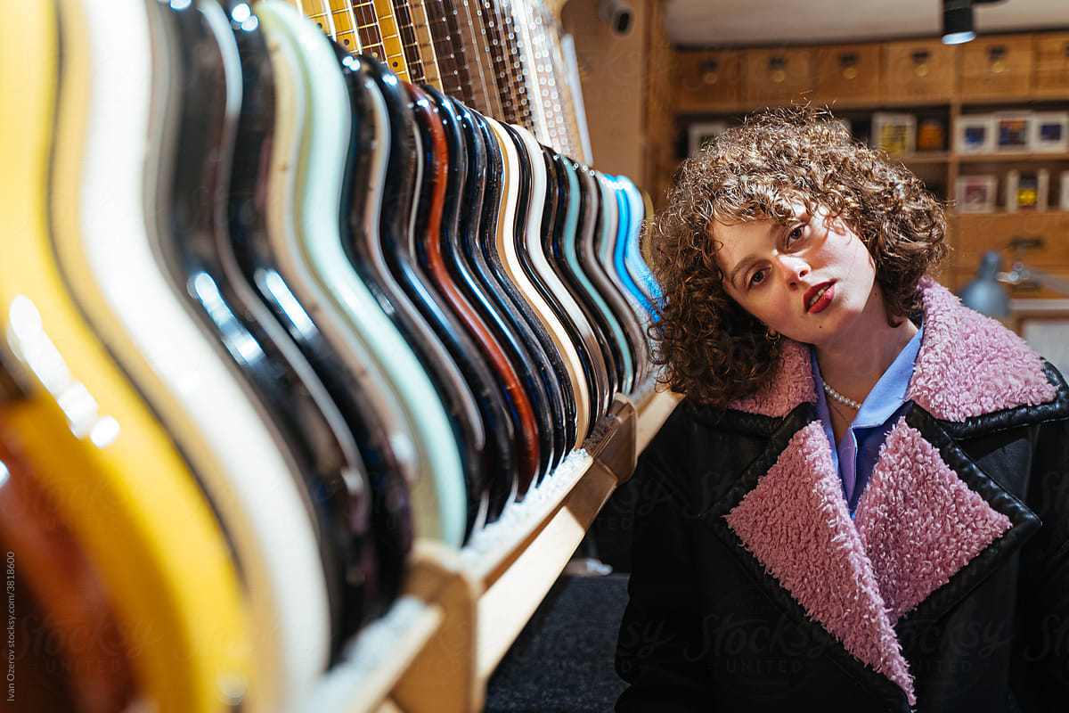 Young female near guitars in music shop