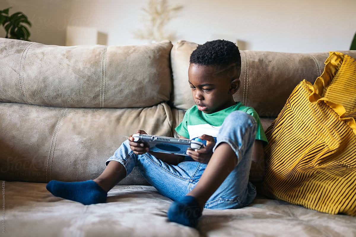 Little boy playing with a game console at home