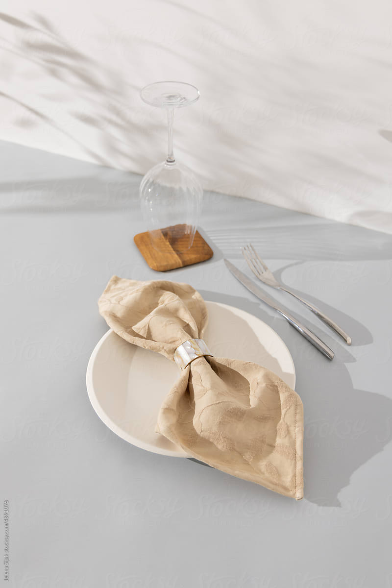 Cotton napkin with the ring, white plate, and cutlery on the table.