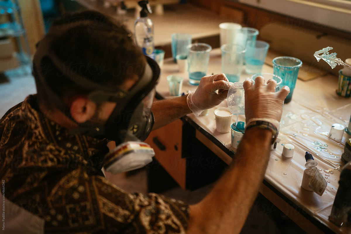 Male master pouring epoxy resin into cups in workshop