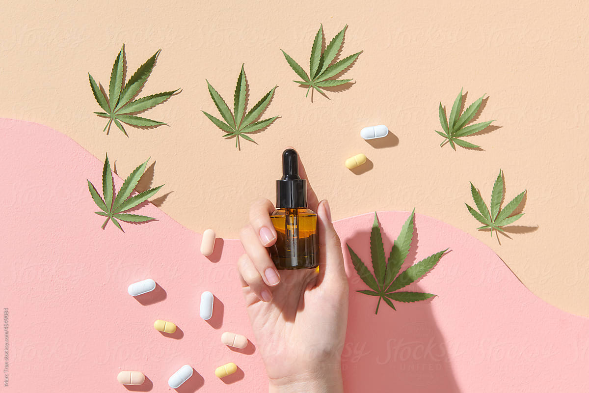 Woman's hand, glass bottles with CBD oil, THC tincture and hemp