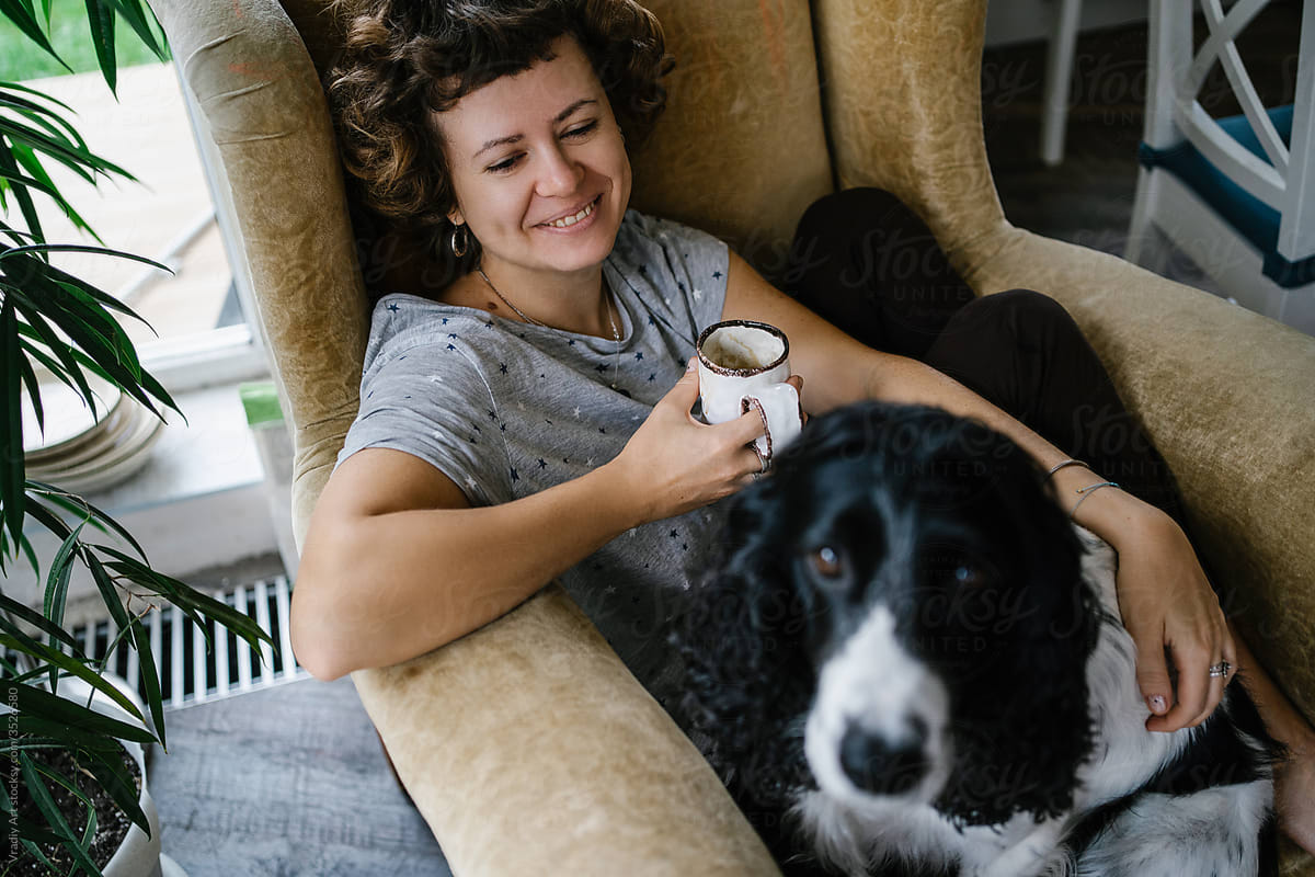 Happy woman with dog resting in armchair
