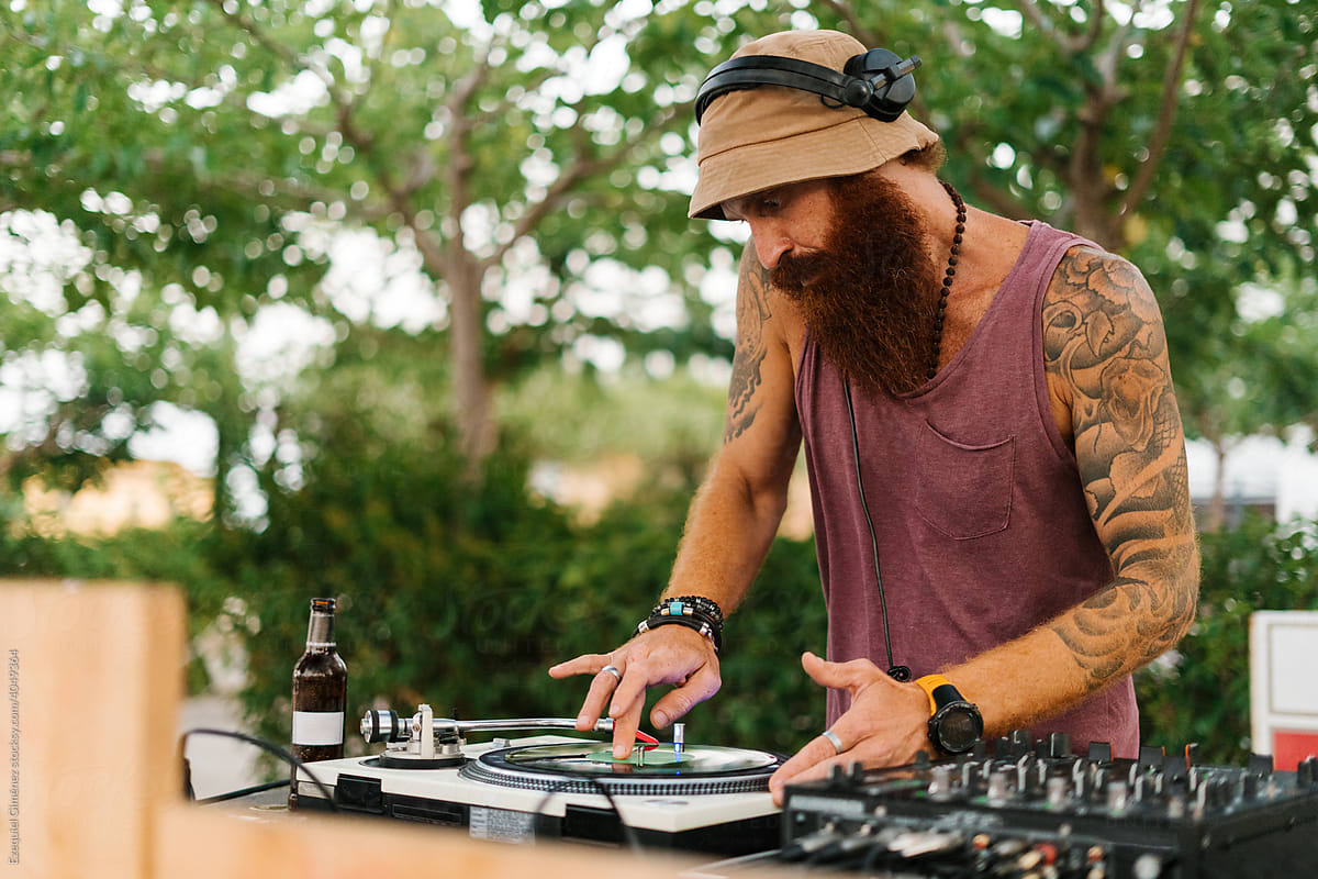 Male DJ playing vinyl during the daytime event.
