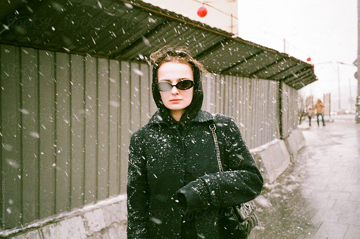 Girl  in sun glasses walking in the street during a snowstorm