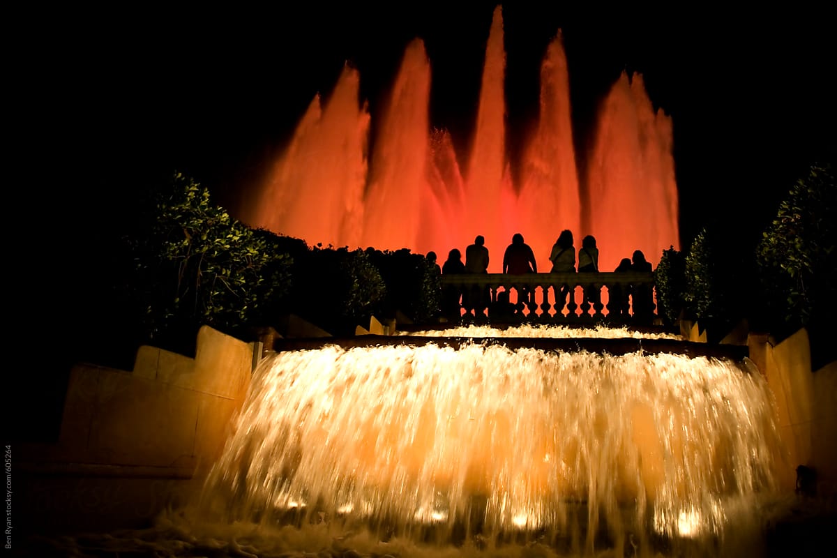 People silhouetted against coloured fountain