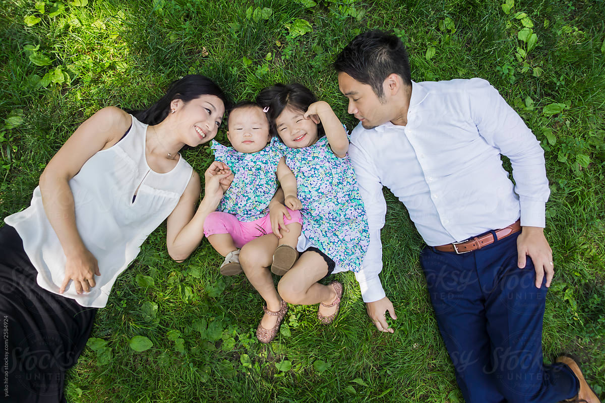 Asian family portrait, lying on the grass, with little kids at park