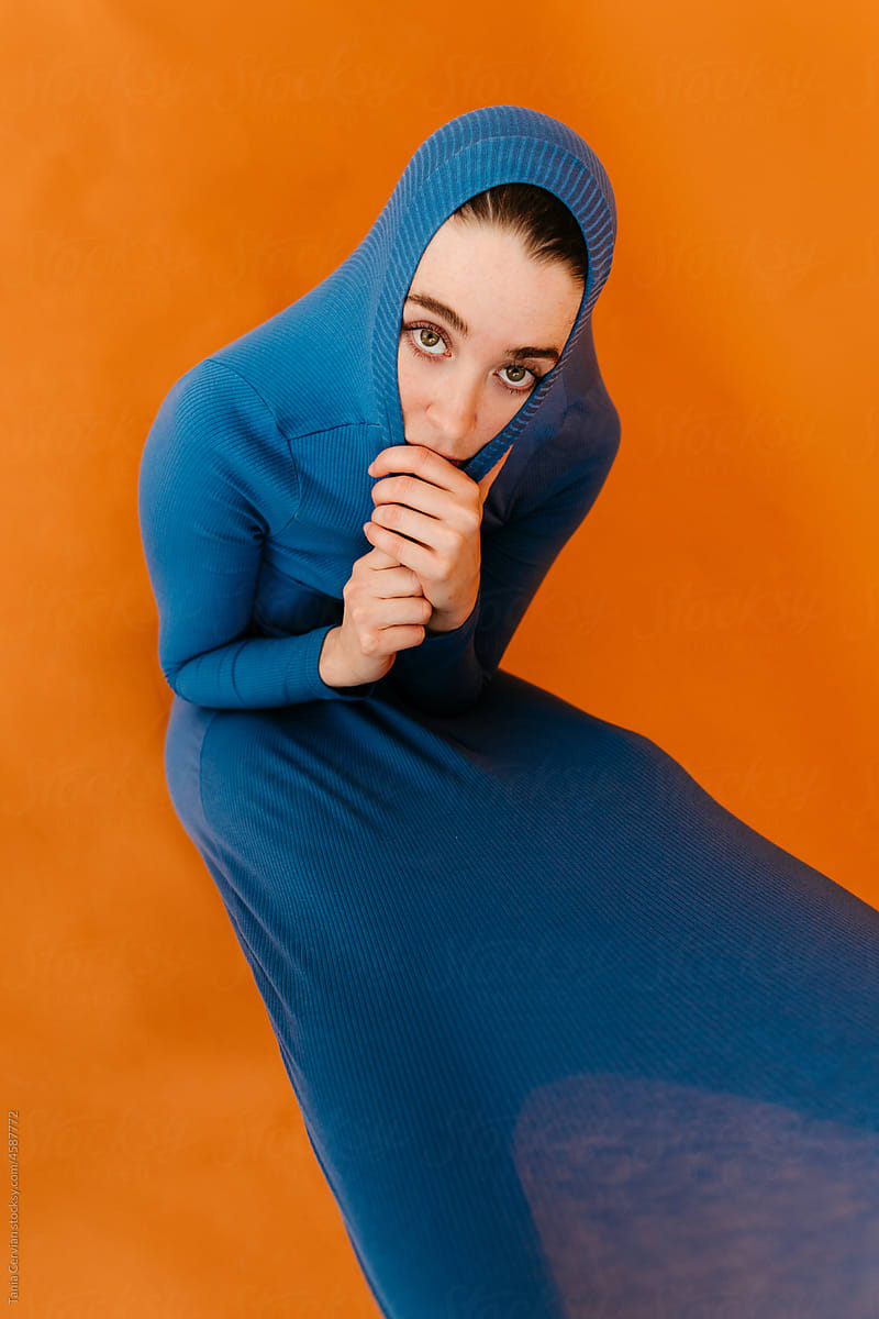 Shy lady covering head with stretch dress in studio