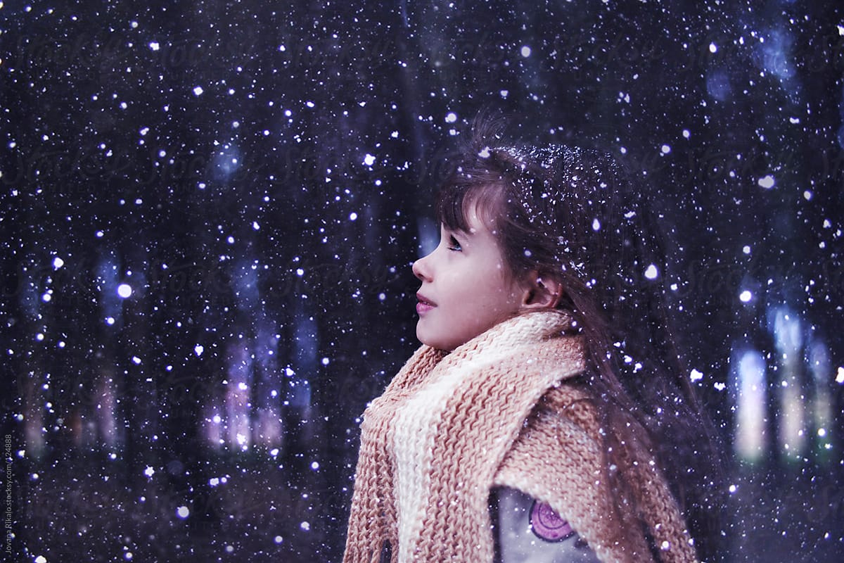 Portrait of a cute little girl watching snow falling