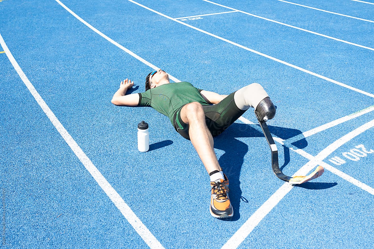 Tired paralympic athlete relaxing on track.