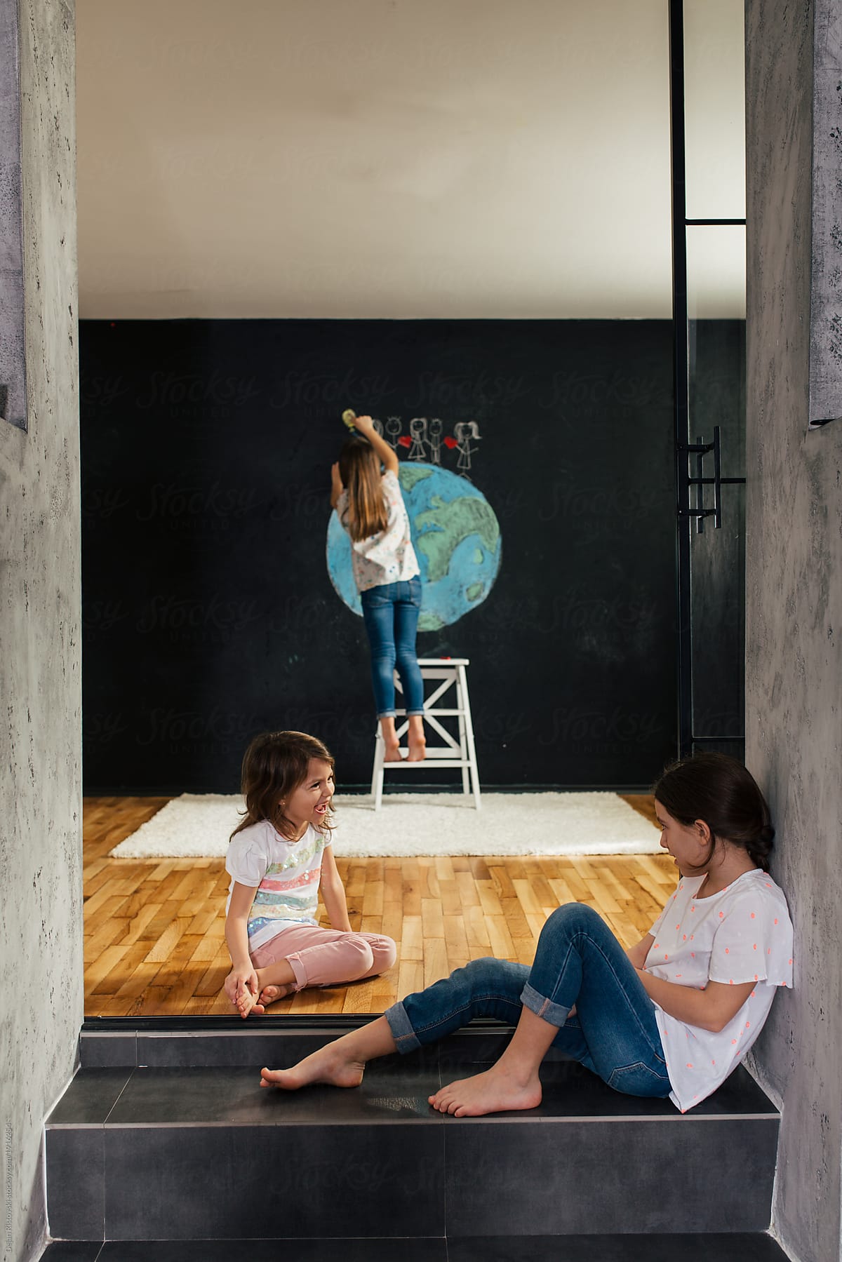 Young girls drawing planet earth on a blackboard